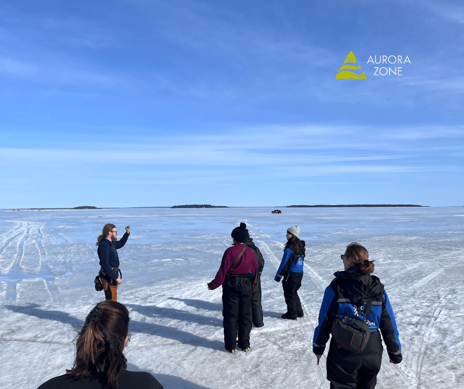 A group of people in Swedish Lapland stood on a frozen lake with blue sky above.